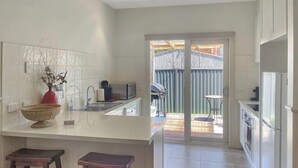 A modern kitchen with a large island, a sink, and a grill area. - River Rock Cottage  Centrally located and Dog friendly (Jamieson)