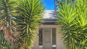A house with a metal roof, a white door, and a small porch area. - River Rock Cottage  Centrally located and Dog friendly (Jamieson)