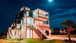 Una casa de varios pisos con un balcón, una escalera y un patio delantero bien iluminado.