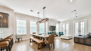 Un amplio salón con mesa de madera, bancos y sofá.