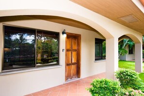 A building entrance with a wooden door, large windows, and a covered walkway. - Cozy Ground-Floor Condo w/ Community Pool, Rancho & Lush Garden Views (Santa Cruz)