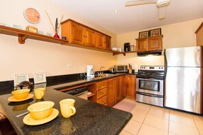 A kitchen with wooden cabinets, a stainless steel refrigerator, a microwave, and a stove. - Cozy Ground-Floor Condo w/ Community Pool, Rancho & Lush Garden Views (Santa Cruz)