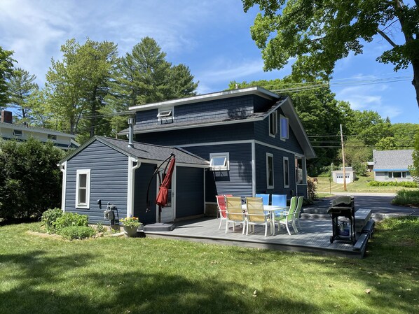 Une maison à deux étages dotée d’un porche abrité, d’un petit garage attenant et d’un espace patio aménagé avec du mobilier d’extérieur.