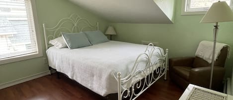 Une chambre à coucher avec un lit, une chaise, une lampe et une fenêtre.