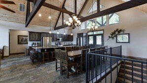 A spacious kitchen with a central island, dark wooden cabinets, and a stone floor.