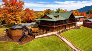 A large, two-story lodge with a green roof, a covered patio, and a stone pathway leading to the entrance.