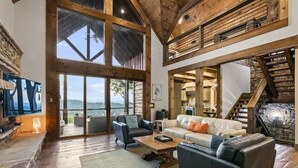 A spacious living area with a large window, a fireplace, and a stone wall. - Already There (Blue Ridge)