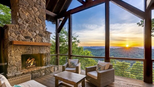 A stone fireplace, wicker furniture, and a view of the sunset over mountains. - Already There (Blue Ridge)