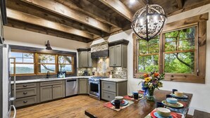 A kitchen with wooden beams, a stone backsplash, and a dining area with a wooden table set for four. - Already There (Blue Ridge)