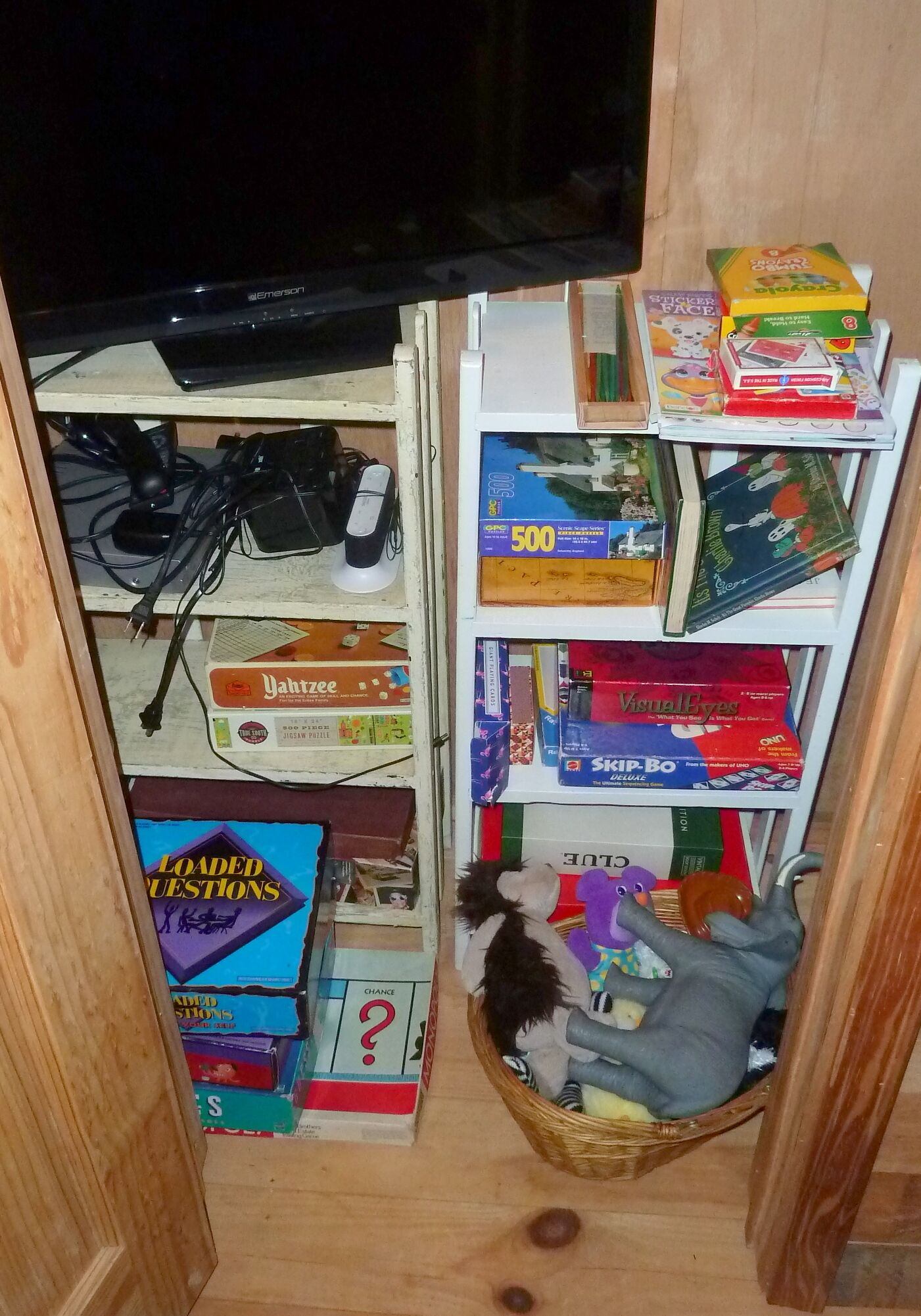Une étagère avec divers jeux de société et un téléviseur.