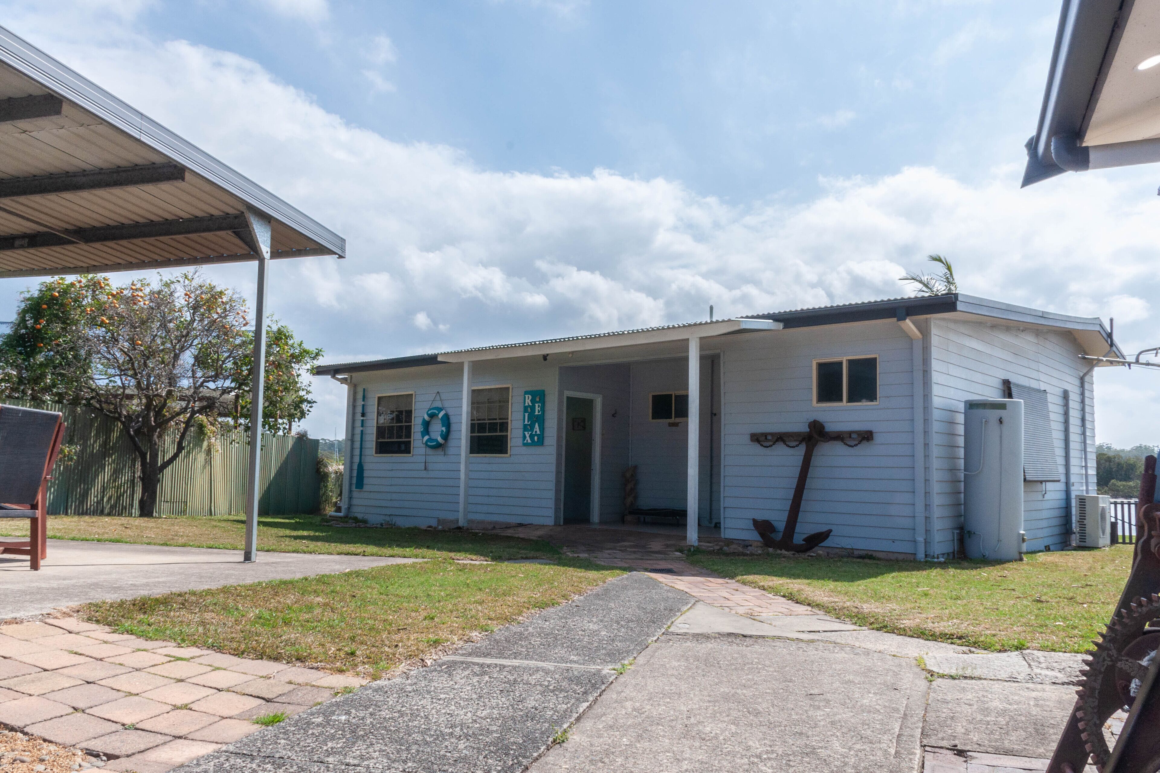 A small, single-story building with a covered porch, a door marked "Relax," and a lifebuoy hanging on the wall.