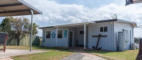 A small, single-story building with a covered porch, a door marked "Relax," and a lifebuoy hanging on the wall.