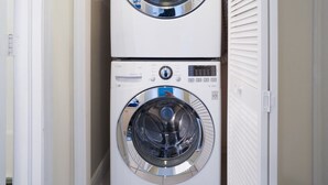 A laundry room with two stacked front-loading washing machines. - Regal Beach Club #633 (Seven Mile Beach)