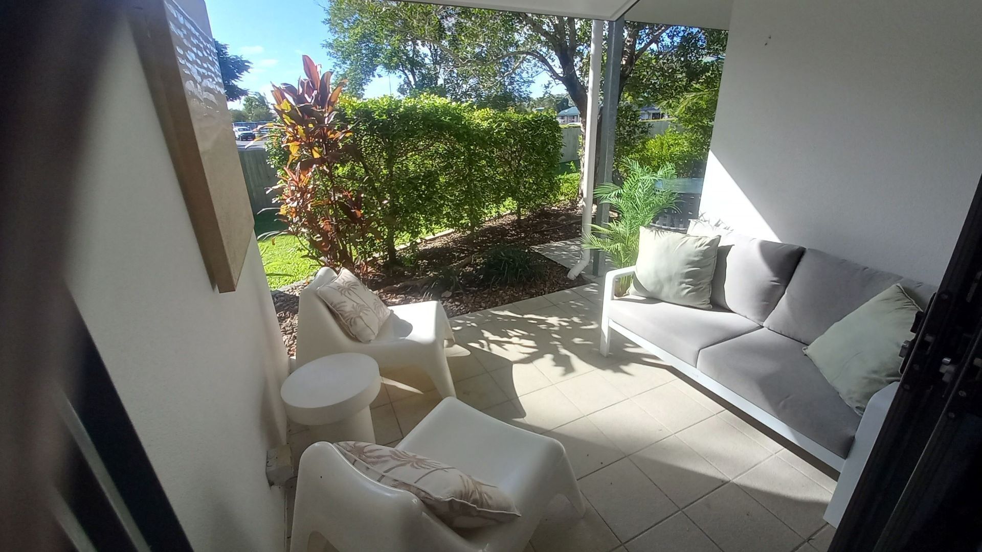 Un patio abrité comprenant un canapé, deux fauteuils et une petite table.