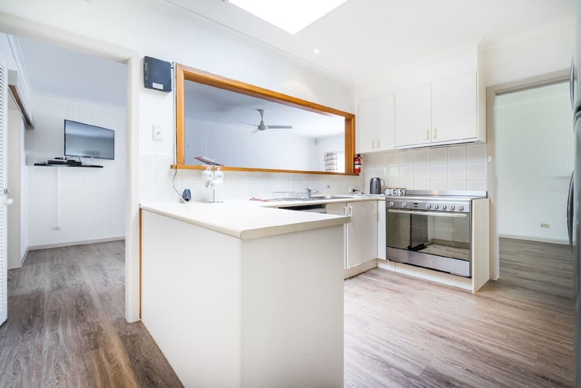 Una cucina moderna con mobili bianchi, forno integrato e una grande isola con lavello.