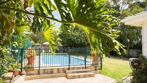 Un jardin avec une piscine, entouré d’une clôture en métal et doté de marches menant à la piscine.