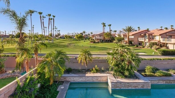 A residential area with a swimming pool, palm trees, and houses with red-tiled roofs. - Ideal Summer getaway home  License #065778 (La Quinta)