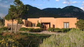 Edificio de una sola planta con techo plano, rodeado de un paisaje natural con montañas al fondo.