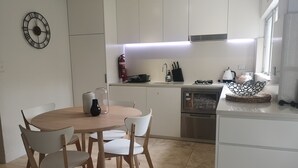 Eine moderne Küche mit weißen Schränken, einem runden Holztisch mit Stühlen und einem eingebauten Backofen.