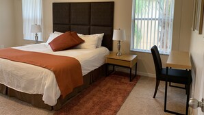 Camera d'albergo con un letto grande, una scrivania, una sedia e una finestra con tende.