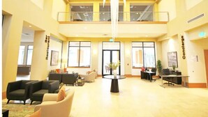 Un'ampia hall con soffitto alto, un tavolo rotondo al centro e zone relax.