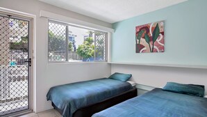 Quarto com duas camas, janela com vista para o exterior e um quadro na parede.