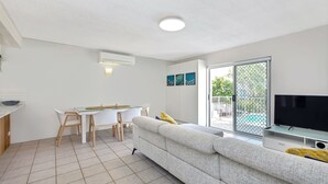 Uma sala de estar moderna com sofá, televisão e espaço de jantar.