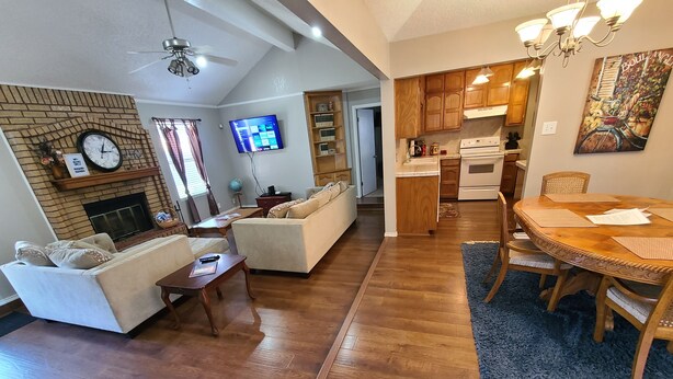 Een woonkamer met een open haard, een televisie en een eethoek met een tafel en stoelen.