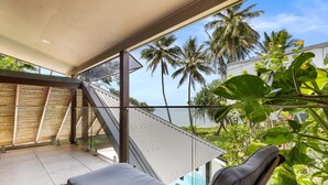 A balcony with a view of palm trees and the ocean.