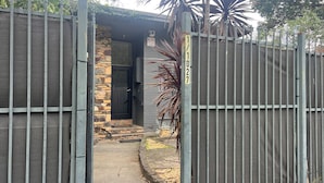 A gated property with a stone wall entrance, a metal gate, and a number sign.