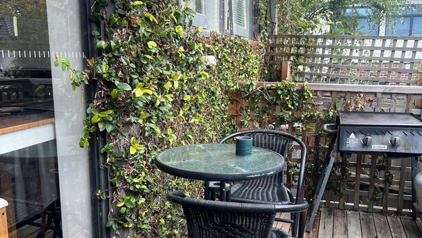 A patio with a round table and chairs, a grill, and a wooden deck.