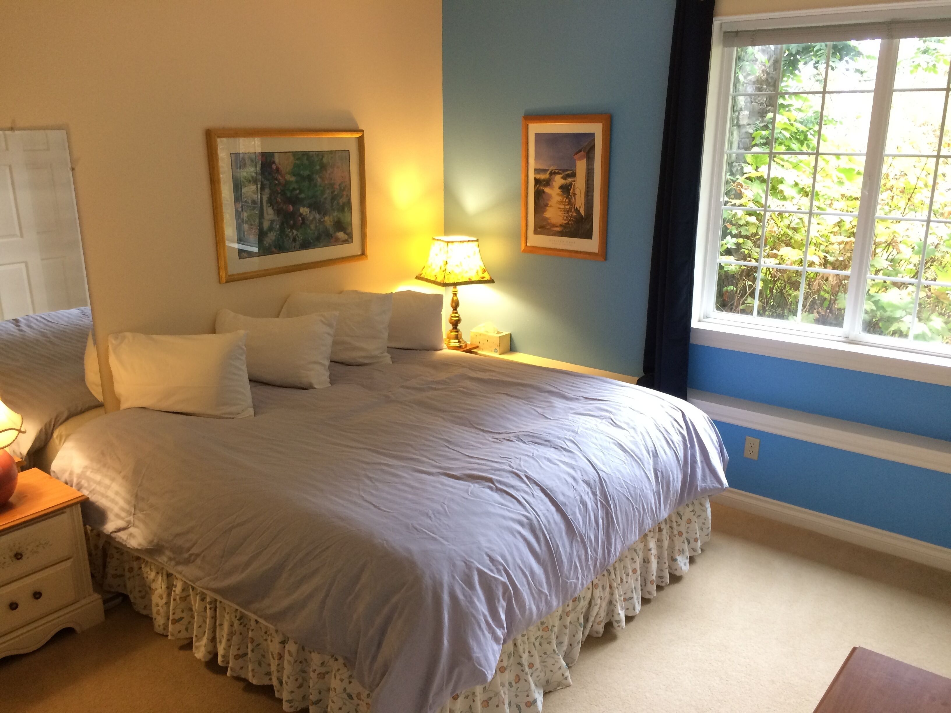 Una camera da letto con un letto grande, due comodini, un tavolino e una finestra con vista sul verde.