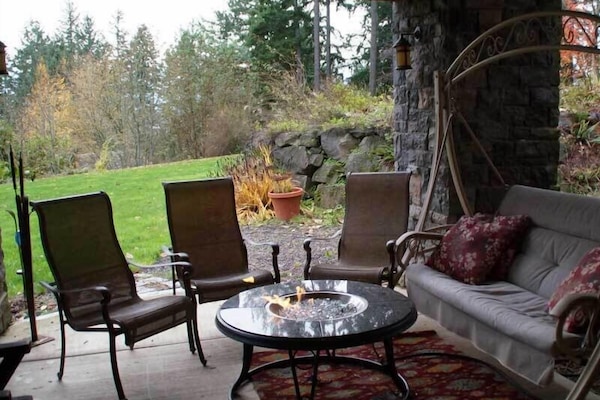 Covered patio with gas fire, swinging bench & expansive view of private lawn.