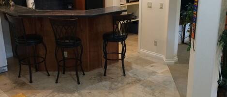 A kitchen with a bar area, wooden cabinets, and a dining table with chairs.
