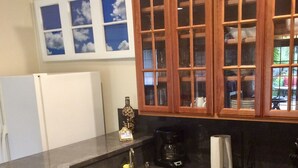 Een keuken met donker granieten aanrechtbladen, houten keukenkastjes, een witte koelkast en een koffiezetapparaat.