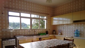 A kitchen with a window, a stove, a sink, and a table with chairs. - House with 5 bedrooms, beautiful view of Pedra Grande. (Atibaia)