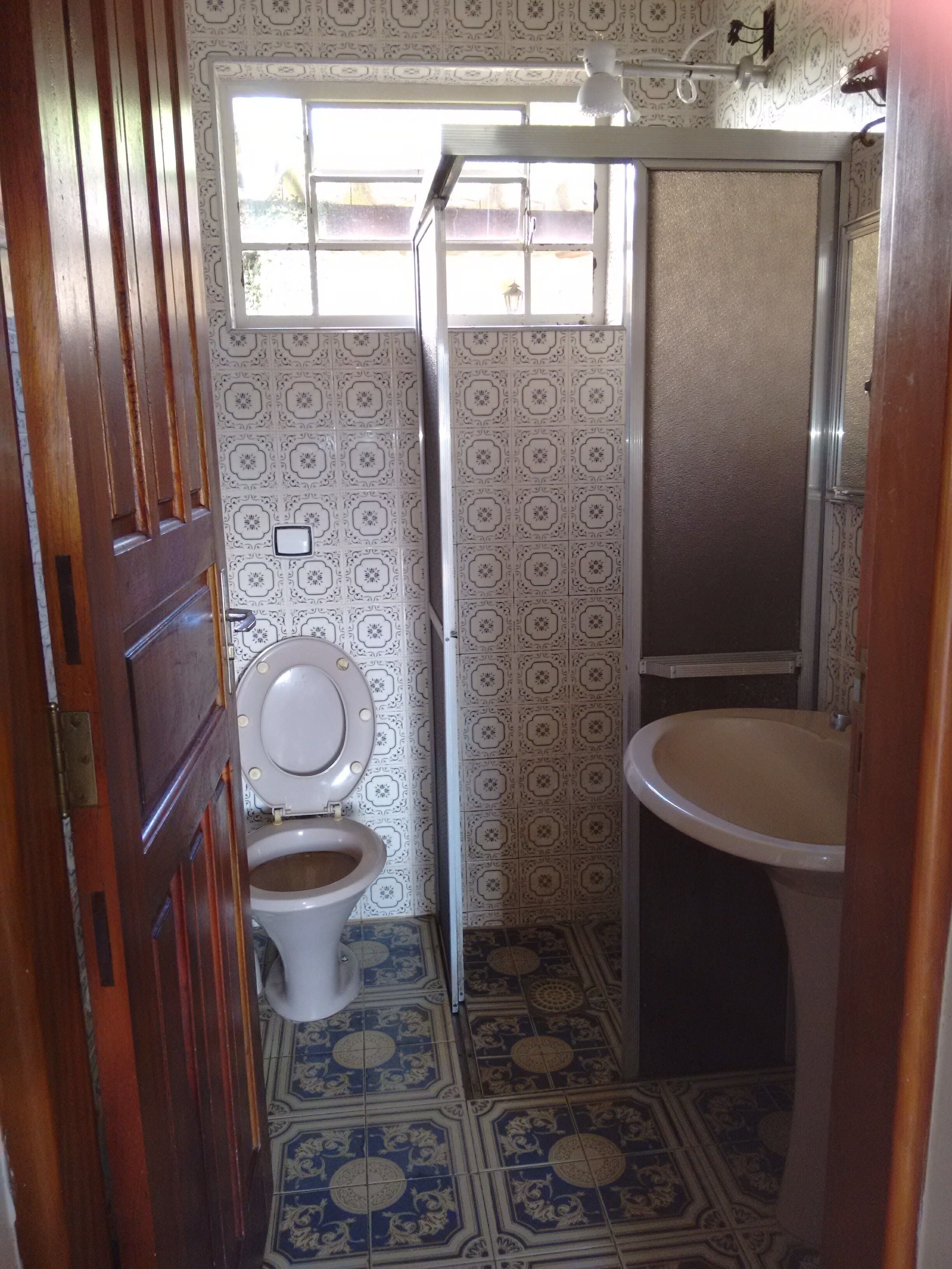A bathroom with a toilet, sink, and patterned floor tiles.