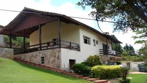 A two-story house with a stone facade, a covered porch, and a small garden with a paved pathway. - House with 5 bedrooms, beautiful view of Pedra Grande. (Atibaia)