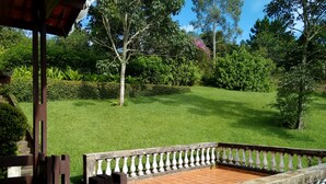 A wooden deck with a white balustrade, surrounded by a well-maintained lawn and various trees. - House with 5 bedrooms, beautiful view of Pedra Grande. (Atibaia)