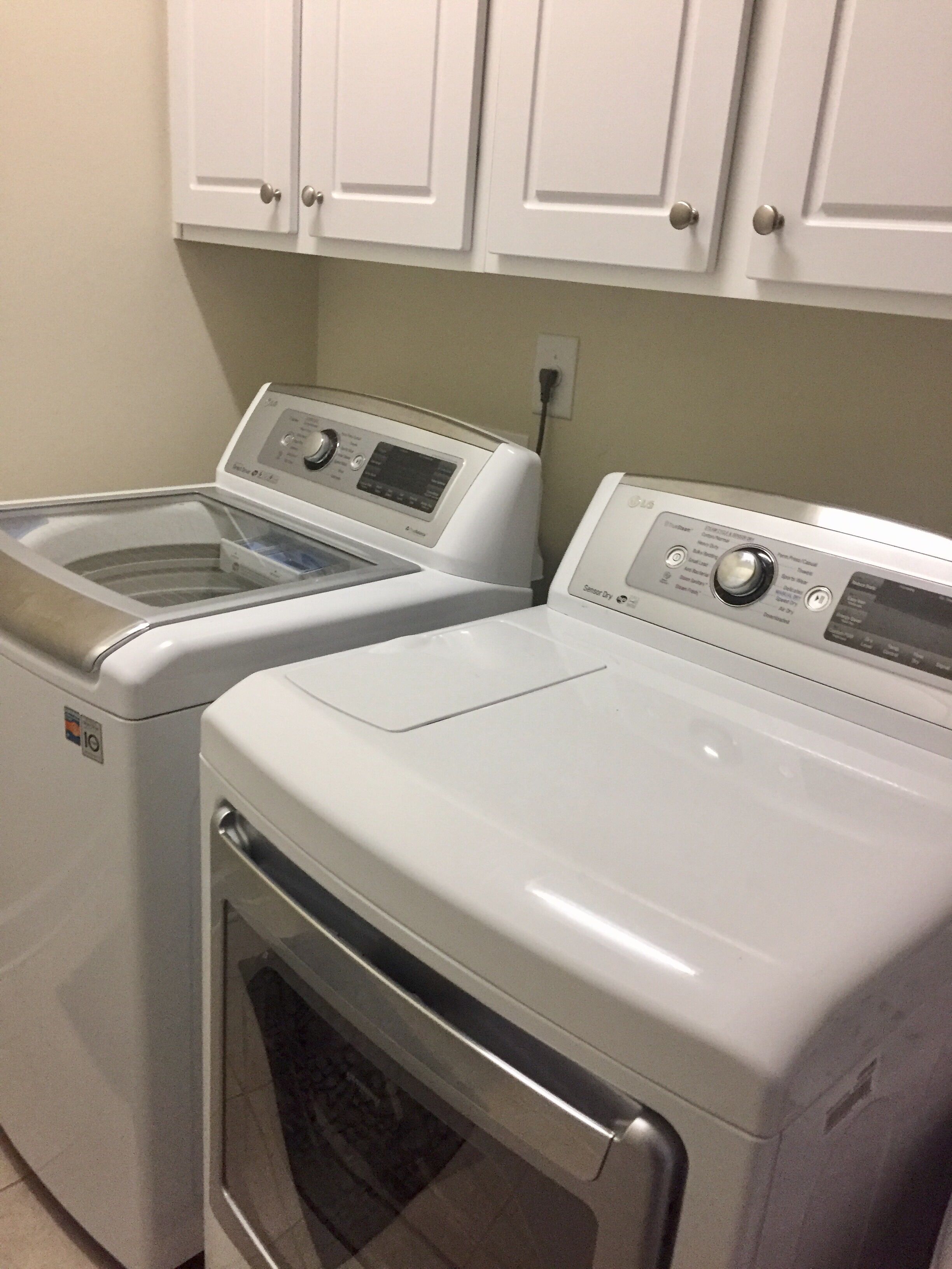 A laundry room with two front-loading washing machines and a dryer.