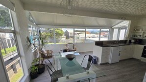 Et moderne køkken med hvide skabe, et glasbord og udsigt til kvarteret.