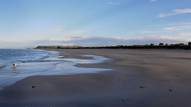 En strand med sandet og bløde bølger.