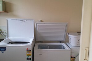 Une cuisine compacte équipée d’un réfrigérateur, d’un congélateur et d’un lave-linge.