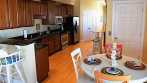 A modern kitchen with wooden cabinets, a central island, and a dining area with a round table set for four.