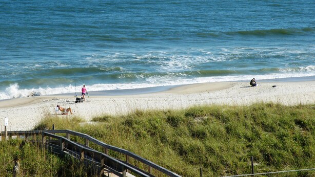 A beach with a wooden walkway leading to the shore.