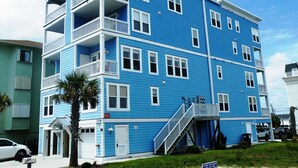 A multi-story residential building with balconies, a garage, and a visible address number.