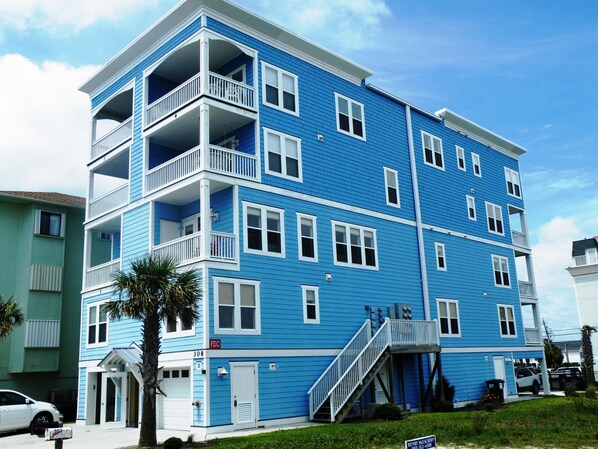 A multi-story residential building with balconies, a garage, and a visible address number.