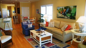 A living room with a striped sofa, a blue armchair, a coffee table, and a dining area with a table and chairs.