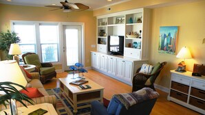 A living room with a sofa, chairs, a coffee table, a television, and a bookshelf.