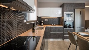 A modern kitchen with a black backsplash, stainless steel appliances, and a wooden countertop. - Mirma Luxury Apartment (Chania)